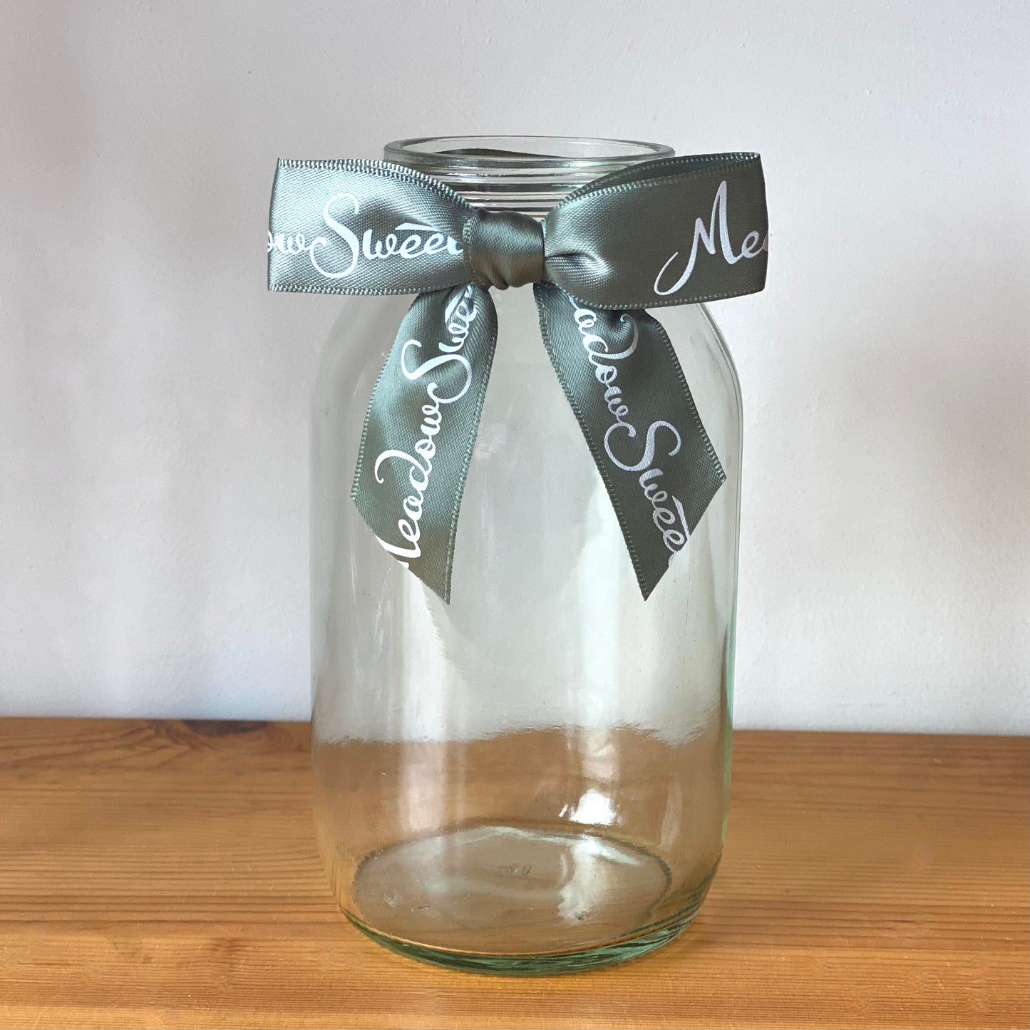 A MeadowSweet recycled-content glass jar with ribbon bow.