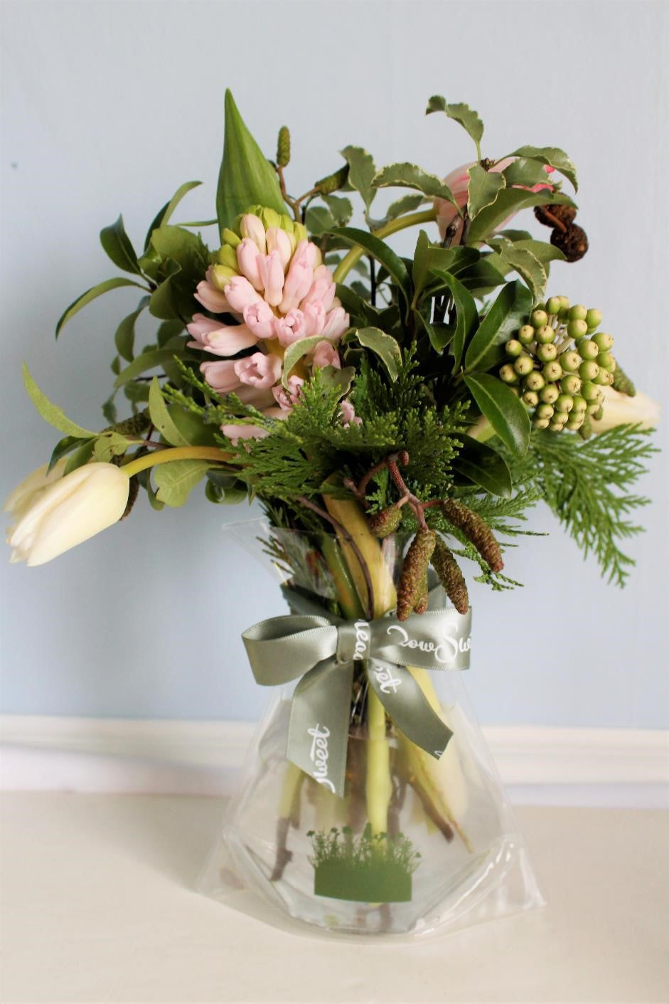 MeadowSweet seasonal posy with British pink and white tulips, pink hyacinth from Holland, fatsia seed head, alder catkins and cones, varigated and green pittosporum, cupressus.