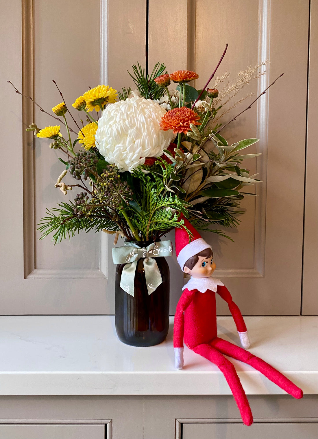 Christmas festive British-grown flower arrangement in a glass jar with elf