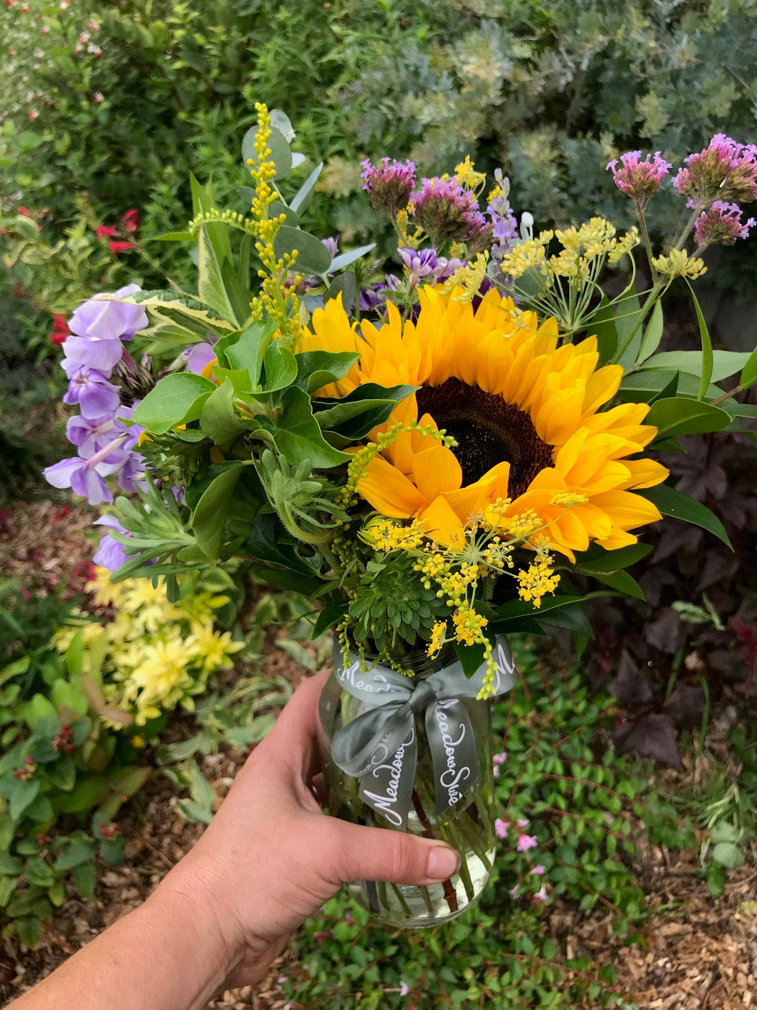 Sunflower and phlox posy in a glass jar in the garden