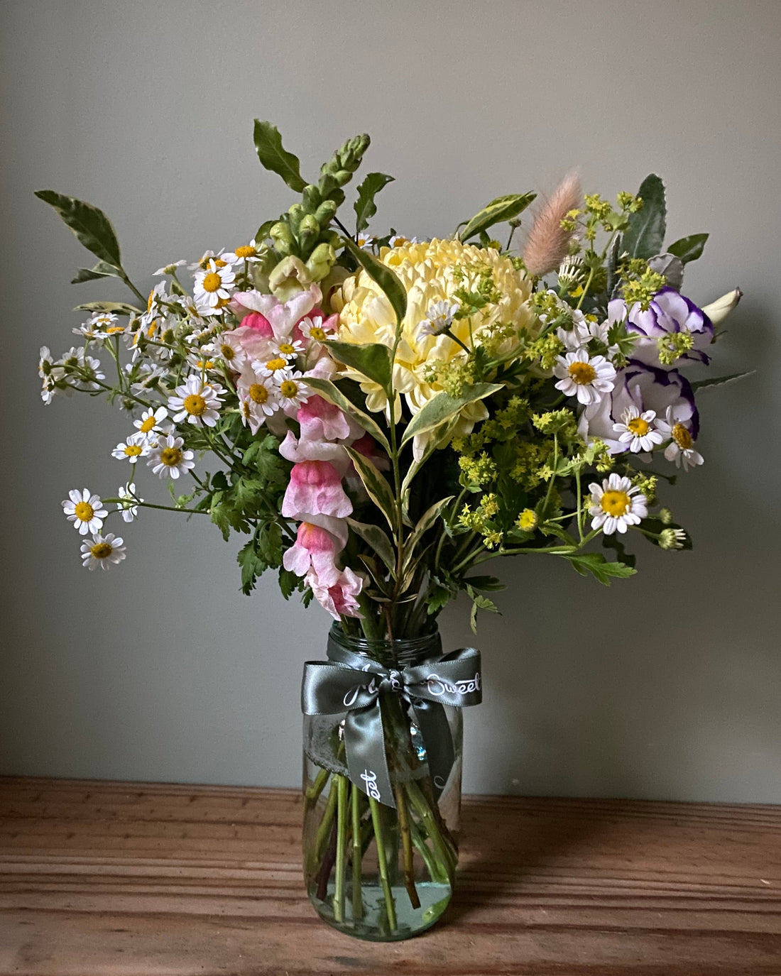 A pretty bunch of British pastel summer flowers in a glass jar