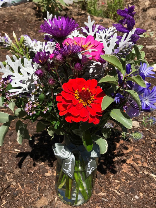 Colourful and bright British homegrown zinnias and daisies in a glass jar