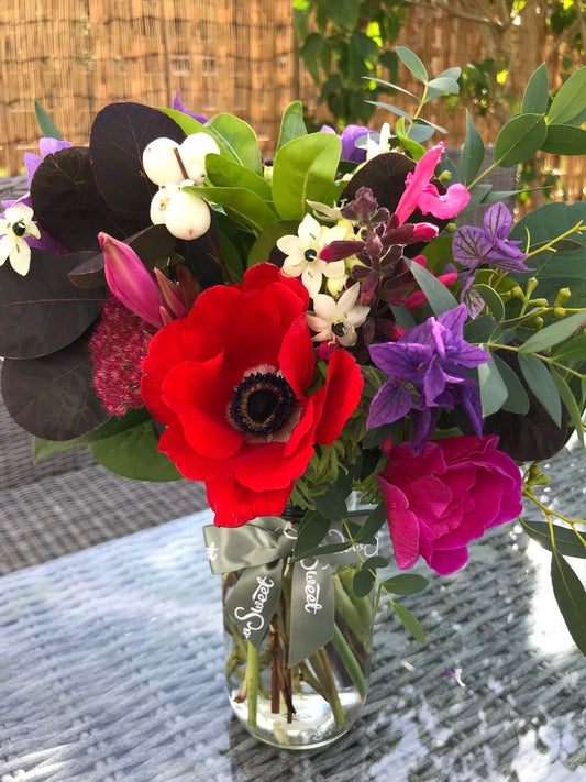 British grown anemone and snowberry posy in a glass jar