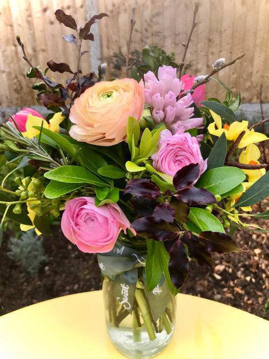 Pretty peaches and pink ranunculus and other British, seasonal Springtime flowers and foliage