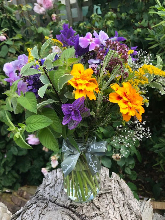 Colourful orange homegrown marigolds and phlox flowers in a glass jar