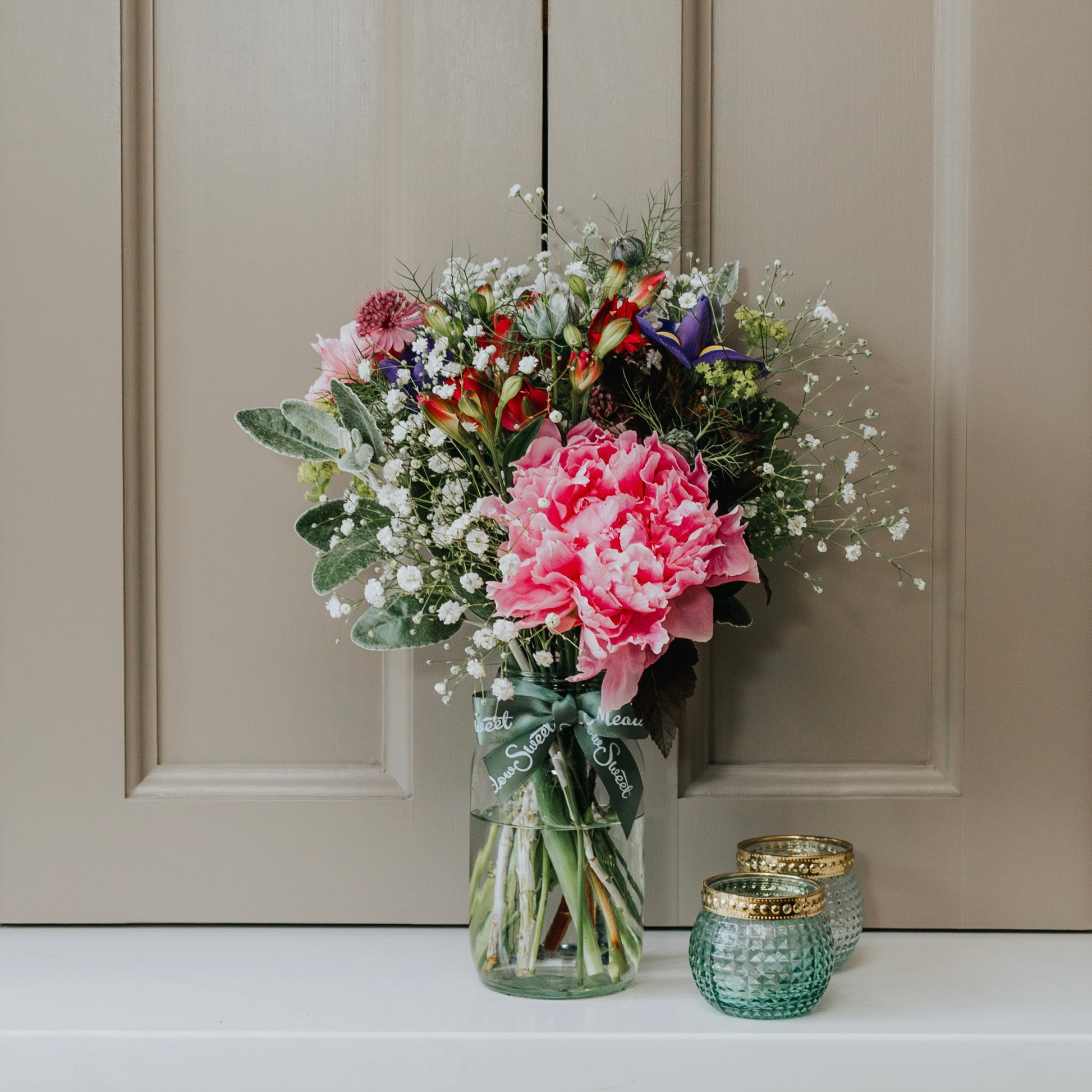 A MeadowSweet posy with British grown flowers including peony and gypsophila in a recycled content glass jar. UK Flower subscription service with free UK delivery.