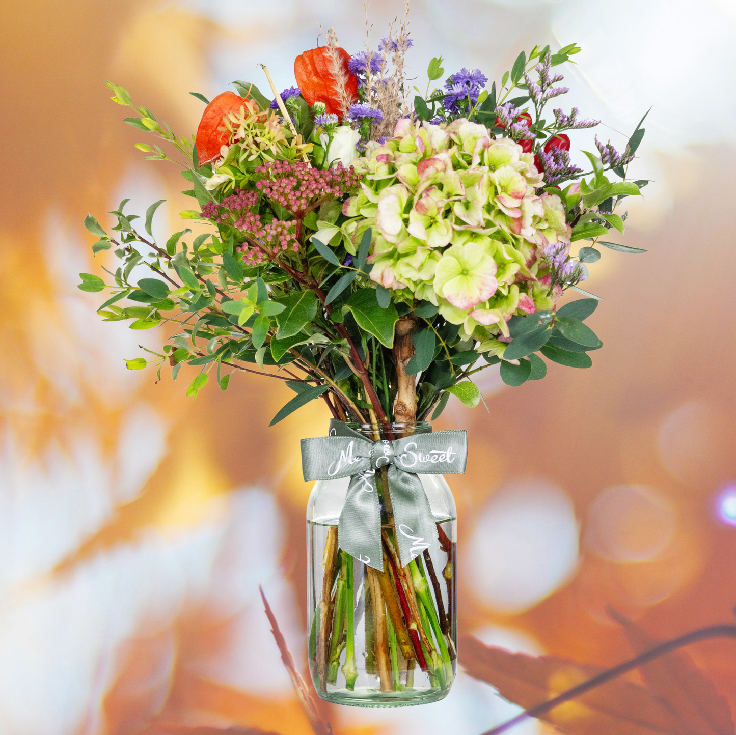 British Grown Autumn Flower Posy with hydrangea In Glass Jar with Autumn leaf backdrop