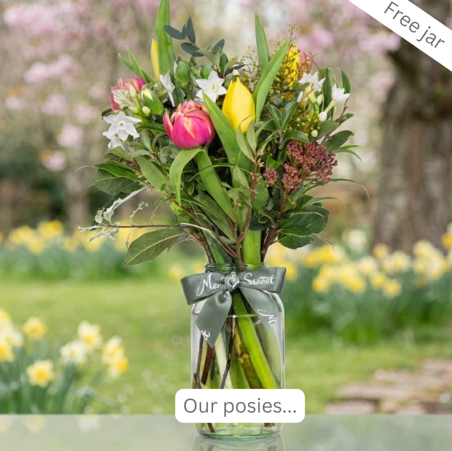 Bouquet of British-grown spring flowers in a glass jar in a pretty English springtime garden setting