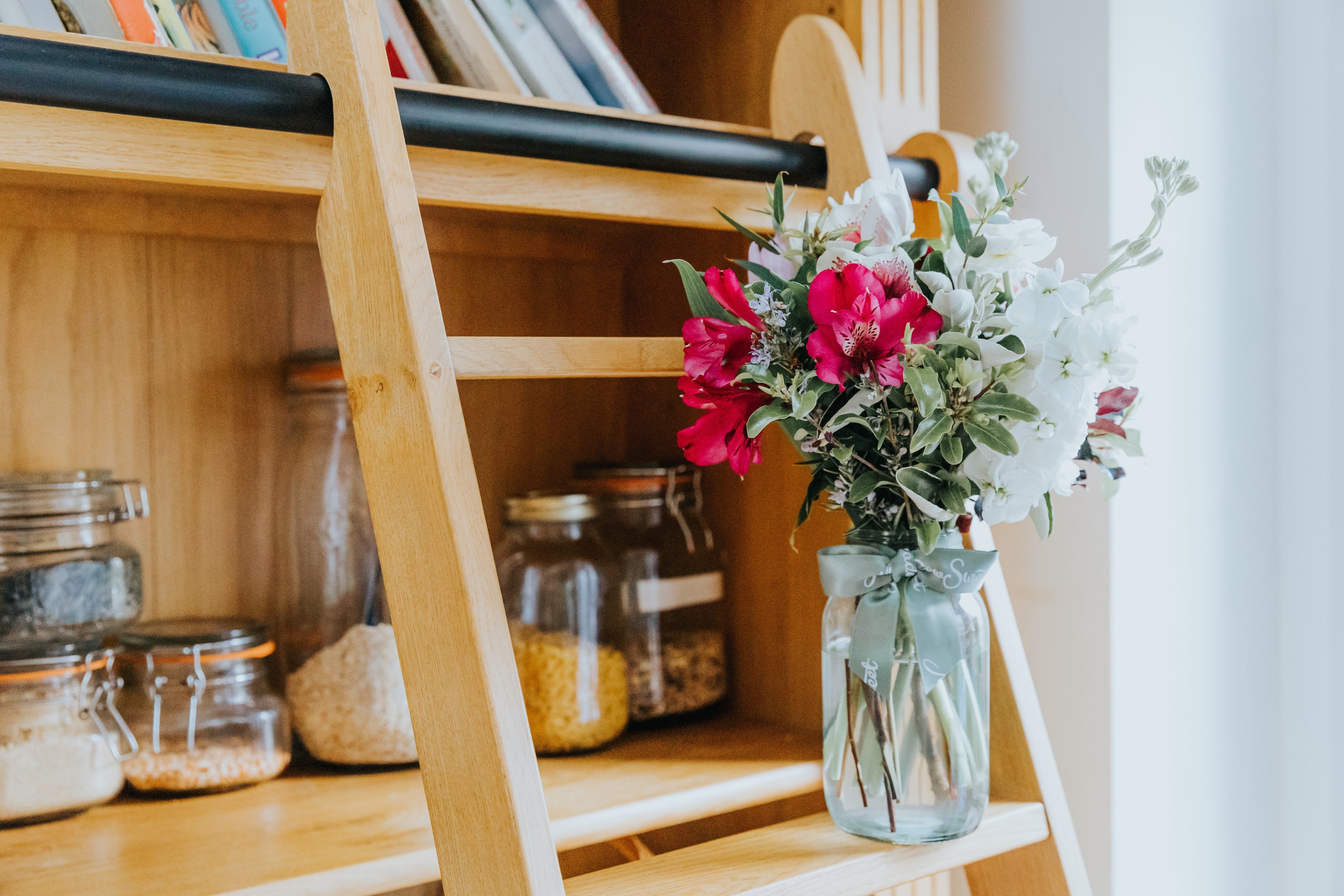 Vase with British flowers on a wooden shelf with jars and books