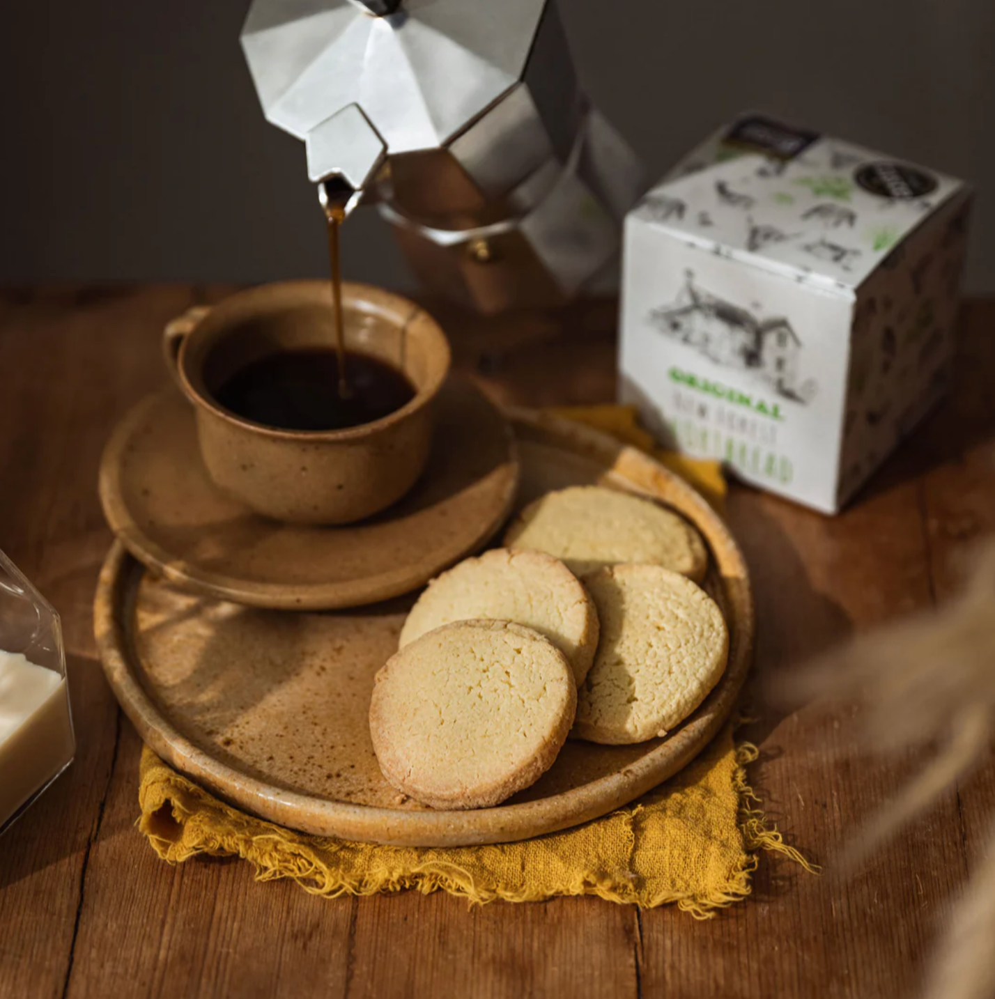 New Forest Shortbread biscuits on a rustic plate with shortbread gift box and a cup of coffee.